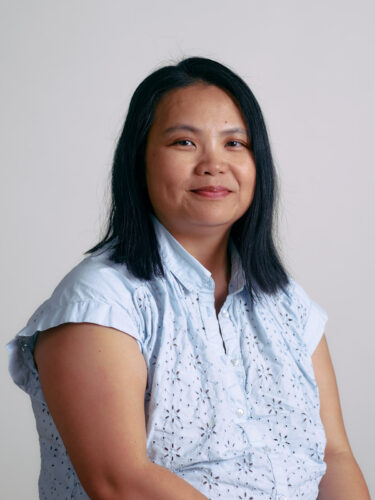A person with shoulder-length black hair in a light blue shirt offers a slight smile against a plain background, embodying the blend of humanity and digital innovation.