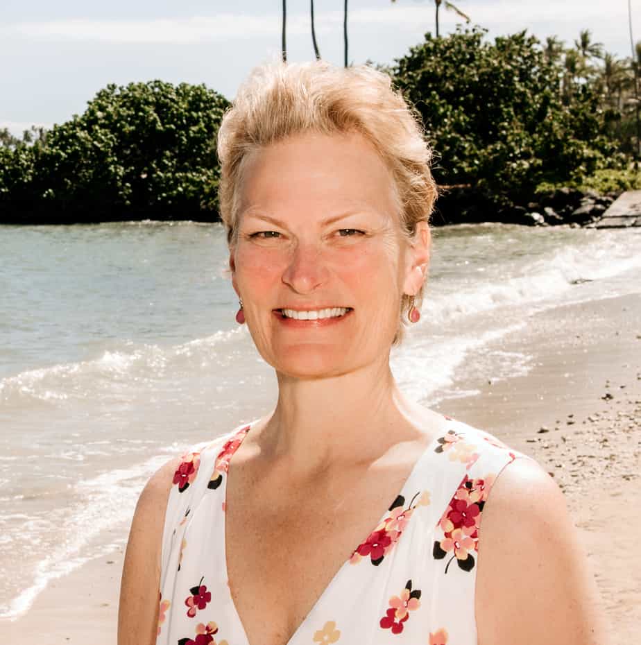 Person smiling on a beach, wearing a white floral dress, embodying the essence of humanity. Waves and trees dance in the background, creating a serene blend of natures beauty and human joy.
