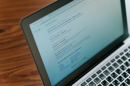 A laptop screen displays Google search results for best babysitting services and apps