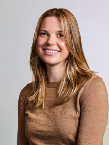 Ellen Jacobs, a smiling woman with blonde hair, wearing a tan sweater.