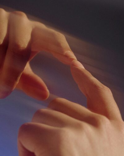 Two hands with index fingers gently touching, creating a soft, blurred artistic effect.