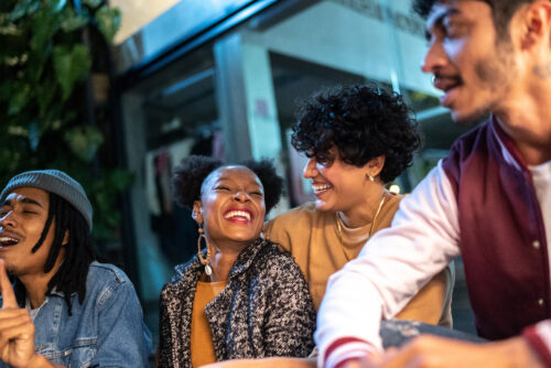 Four friends laughing and enjoying time together outdoors at night.